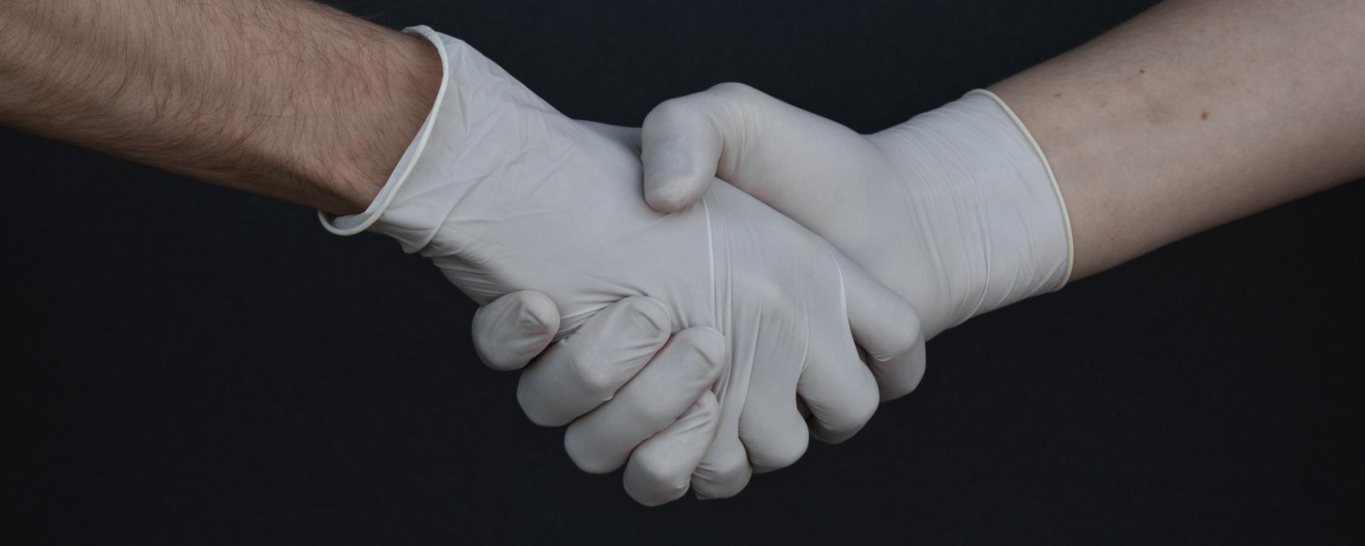 People Shaking Hands in Latex Gloves by Branimir Balogovic
