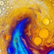 Photograph of bubbles on a coloured, irridescant background, resembling oil on water. Photo by Lanju Fotografie on Unsplash.