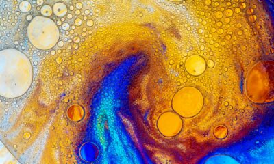 Photograph of bubbles on a coloured, irridescant background, resembling oil on water. Photo by Lanju Fotografie on Unsplash.